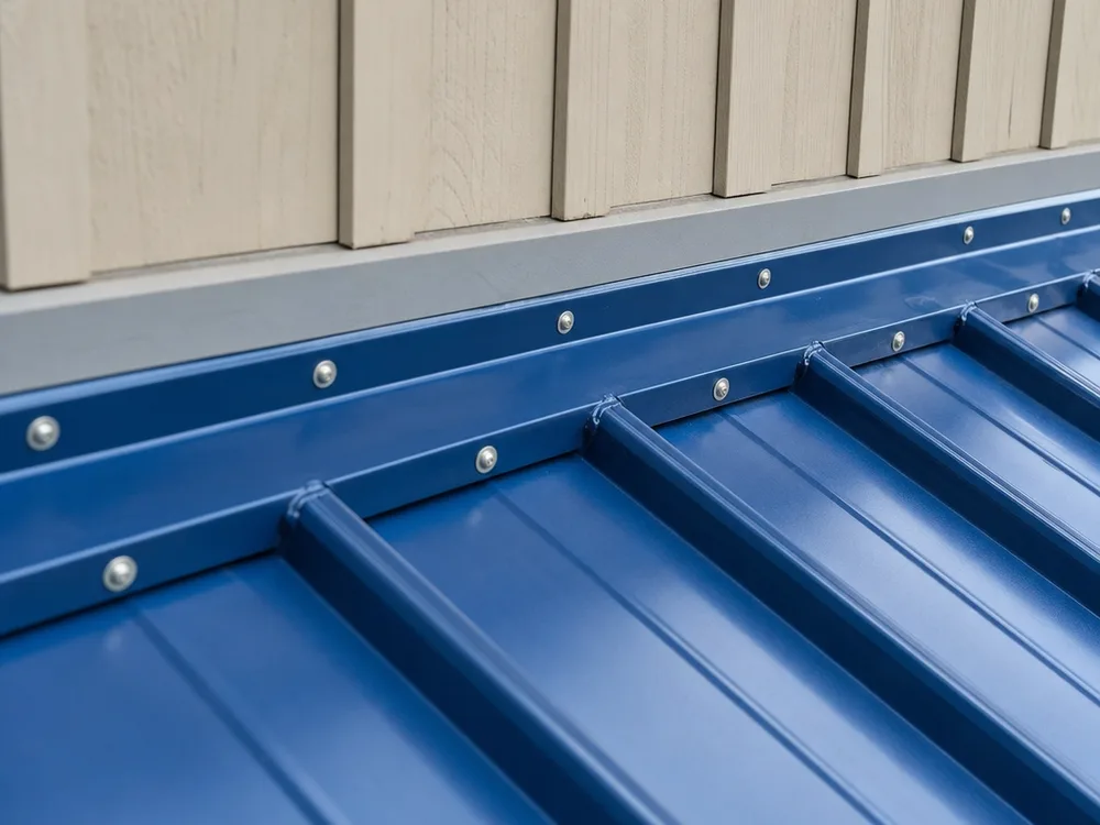 Close-up of metal roof flashing and fasteners at a roof-to-wall transition with clean trim lines and sealed penetrations